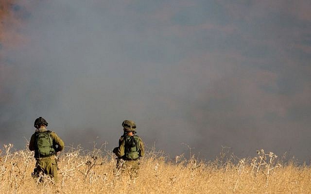 IDF soldiers stand near a large brush fire outside Kfar Sold in the Golan Heights sparked by four missiles fired from the Syrian side of the Israeli-Syrian border on August 20, 2015. (Basel Awidat/Flash90) IDF soldiers stand near a large brush fire outside Kfar Sold in the Golan Heights sparked by four missiles fired from the Syrian side of the Israeli-Syrian border on August 20, 2015. (Basel Awidat/Flash90)