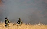 Illustrative:Two IDF soldiers stand amid a large fire raging near Kfar Sold, caused by missiles fired from the Syrian side of the Israeli-Syrian border and hitting open areas in the Golan Heights in northern Israel on August 20, 2015. (Basel Awidat/Flash90)