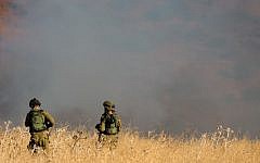 Illustrative:Two IDF soldiers stand amid a large fire raging near Kfar Sold, caused by missiles fired from the Syrian side of the Israeli-Syrian border and hitting open areas in the Golan Heights in northern Israel on August 20, 2015. (Basel Awidat/Flash90)