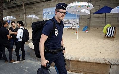 A French police officer arrives at the Paris Tel Aviv Beach on the banks of the Seine River in Paris, France, Thursday, Aug. 13, 2015 (AP Photo/Francois Mori)