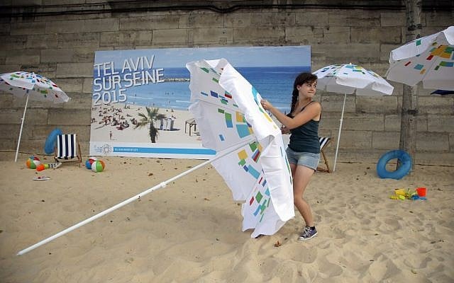 A volunteer installs a sun umbrella on the sand as part of the Paris Tel Aviv Beach on the banks of the Seine Rive in Paris, France, Thursday, Aug. 13, 2015 (AP Photo/Francois Mori) A volunteer installs a sun umbrella on the sand as part of the Paris Tel Aviv Beach on the banks of the Seine Rive in Paris, France, Thursday, Aug. 13, 2015 (AP Photo/Francois Mori)