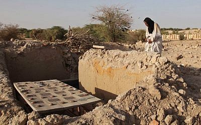 In this Friday, April 4, 2014 file photo, Mohamed Maouloud Ould Mohamed, a mausoleum caretaker, prays at a damaged tomb in Timbuktu, Mali. (AP Photo/Baba Ahmed, File)