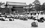 In this Aug. 15, 1945 photo, Japanese people kneel in front of the Imperial Palace in Tokyo as Emperor Hirohito announced on radio that Japan was defeated in the World War II.  (Kyodo New via AP)