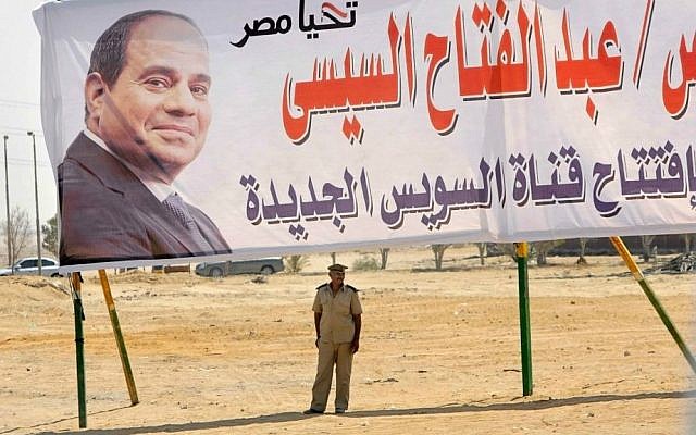 A policeman stands alert under a billboard with the photo of Egyptian President Abdel-Fattah el-Sissi at the Cairo-Ismailia desert road in Egypt, Thursday, Aug. 6, 2015. (AP Photo/Amr Nabil)