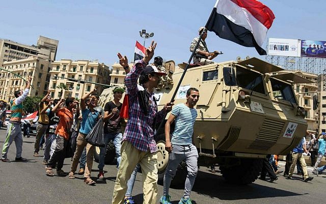 Egyptians wave the national flag and walk alongside a military vehicle as they celebrate the opening of the Suez Canal in down town Cairo, Thursday, Aug. 6, 2015. (AP Photo/Mohamed Elraai)