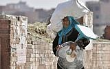 An Egyptian farmer carries an electric fan as she walks through a Cairo street , Egypt, Tuesday, Aug. 11, 2015. (AP Photo/Amr Nabil)