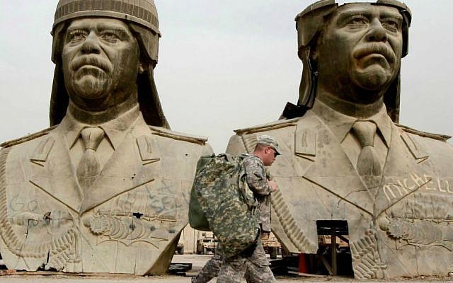 In this March 20, 2009, file photo, US Army soldiers stroll past two bronze busts of former Iraqi President Saddam Hussein in the Green Zone in Baghdad, Iraq. (AP Photo/Hadi Mizban, File)