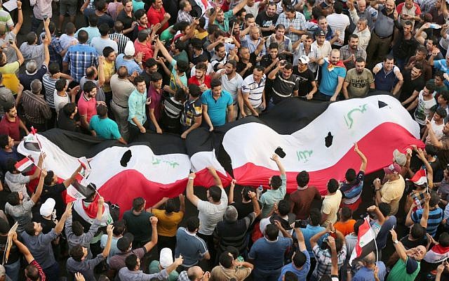 Protesters chant anti-Iraqi government slogans as they carry a large national flag during a protest in Tahrir Square in Baghdad, Iraq, August 7, 2015. (AP/Karim Kadim) Protesters chant anti-Iraqi government slogans as they carry a large national flag during a protest in Tahrir Square in Baghdad, Iraq, August 7, 2015. (AP/Karim Kadim)