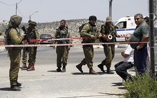 Israeli soldiers secure the scene after a Palestinian man wounded an Israeli soldier with a knife at a crossing between Israel and West Bank north of Jerusalem, August 15, 2015. (AP/Mahmoud Illean) Israeli soldiers secure the scene after a Palestinian man wounded an Israeli soldier with a knife at a crossing between Israel and West Bank north of Jerusalem, August 15, 2015. (AP/Mahmoud Illean)