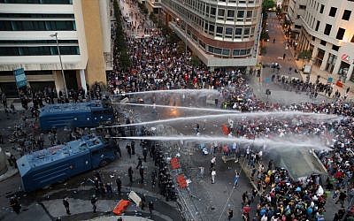 Lebanese activists shout anti-government slogans as they are sprayed by riot police using water cannons during a protest against the ongoing trash crisis, in downtown Beirut, Lebanon, Sunday, Aug. 23, 2015.  (AP Photo/Bilal Hussein)