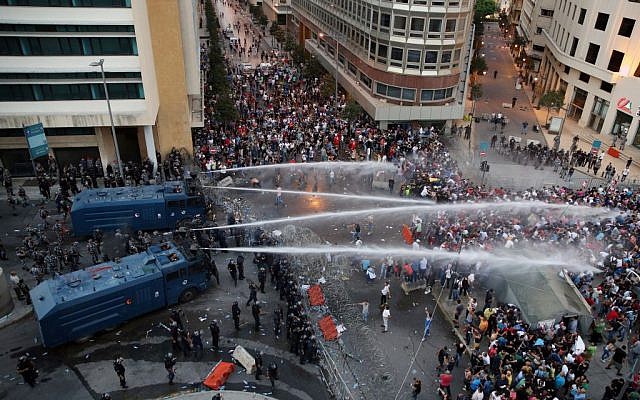 Lebanese activists shout anti-government slogans as they are sprayed by riot police using water cannons during a protest against the ongoing trash crisis, in downtown Beirut, Lebanon, Sunday, Aug. 23, 2015.  (AP Photo/Bilal Hussein)