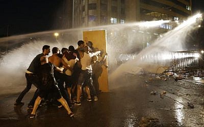 Lebanese activists shout anti-government slogans as they are sprayed by riot police using water cannons during a protest against the ongoing trash crisis, in downtown Beirut, Lebanon, Sunday, Aug. 23, 2015. (AP/Hassan Ammar)
