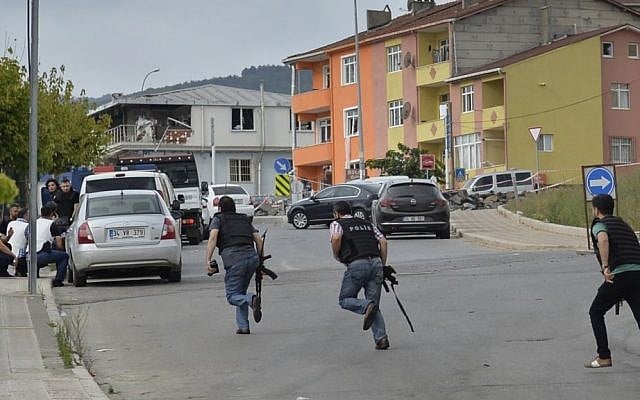 Turkish police officers run for cover during a gunfight near the site of an overnight explosion at a police station in Istanbul's Sultanbeyli neighborhood, August 10, 2015. (AP/Akin Celiktas) 