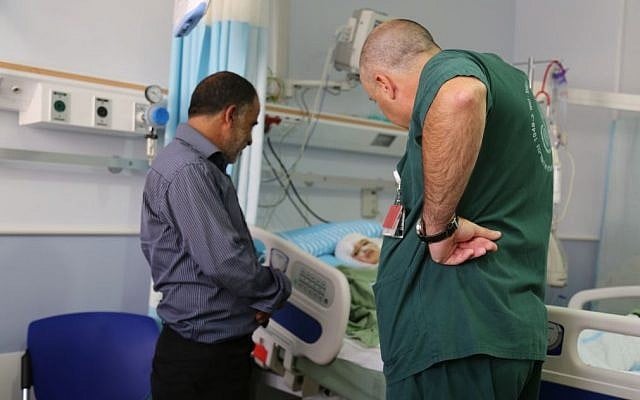 Hussein Dawabsha and a doctor stand next to Ahmed Dawabsha's hospital gurney (Eric Cortellessa/Times of Israel)