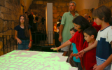 A group of visitors interacting with Ezri Tarazi’s table, 'Remapping,' 2015. (Oded Antman)