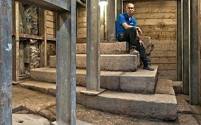 Joe Uziel, co-director of an Israel Antiques Authority excavation, sitting atop the stepped structure from the Second Temple period in Jerusalem. (Shai Halevy/ Israel Antiquities Authority)