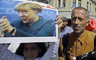 A migrant girl holds a poster of German Chancellor Angela Merkel as migrants walk in Budapest downtown after leaving the transit zone of the main train station, on September 4, 2015 intent on walking to the Austrian border.  (AFP PHOTO / PETER KOHALMI)