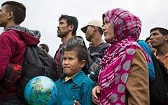 A migrant boy plays with a globe ball as hundreds of refugees wait for a bus after crossing the Hungarian-Austrian border in Nickelsdorf on September 5, 2015. (Vladimir Simicek/AFP)
