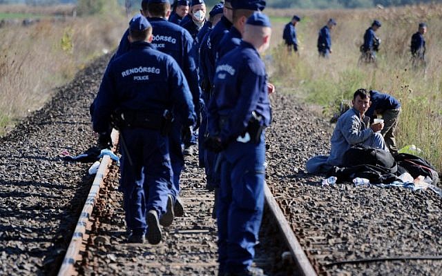 A young refugee man watches policemen walking to take a new position at a migrant collection point near Roszke village of the Hungarian-Serbian border on September 8, 2015. (AFP/CSABA SEGESVARI)