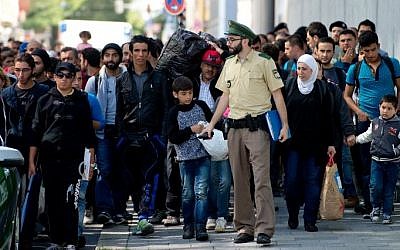 A policemen leads migrants to a temporary shelter upon their arrival in Munich from Budapest on September 12, 2015. (AFP/ DPA / SVEN HOPPE) A policemen leads migrants to a temporary shelter upon their arrival in Munich from Budapest on September 12, 2015. (AFP/ DPA / SVEN HOPPE)