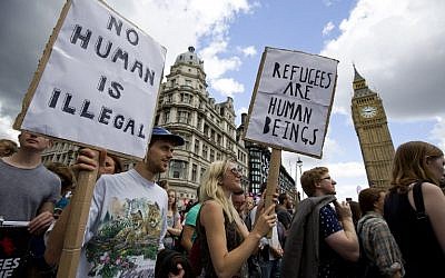 Demonstrators hold placards as pass the Houses of Parliament during a pro-refugee rally in central London on September 12, 2015. (AFP PHOTO / JUSTIN TALLIS)