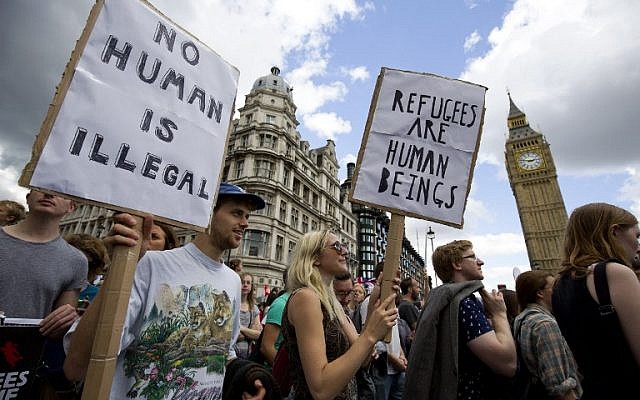 Demonstrators hold placards as pass the Houses of Parliament during a pro-refugee rally in central London on September 12, 2015. (AFP PHOTO / JUSTIN TALLIS)
