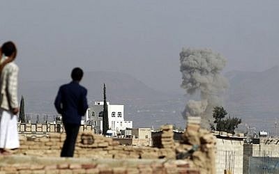 Yemenis look as smoke billows from buildings after reported air-strikes by the Saudi-led coalition on arms warehouses at al-Dailami air base,north of capital Sanaa, on September 16, 2015. (Mohammed Huwais/AFP)