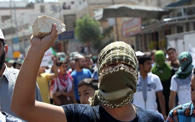 Illustrative: A Palestinian protester in Hebron holds a stone during clashes with Israeli security forces following an anti-Israeli protest after the weekly Friday prayers on September 18, 2015. AFP  PHOTO / HAZEM BADER