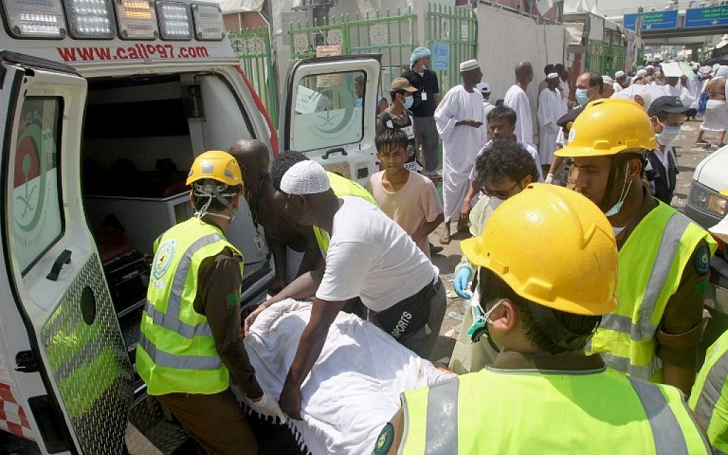 Saudi emergency personnel and Hajj pilgrims load a wounded person into an ambulance at the site where at least 450 were killed and hundreds wounded in a stampede in Mina, near the holy city of Mecca, at the annual hajj in Saudi Arabia on September 24, 2015.(AFP PHOTO / STR)