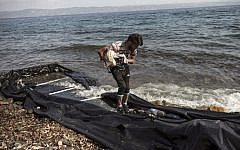 A Syrian migrant collects his belongings as he arrives on the shore of Lesbos island, after crossing the Aegean sea from Turkey on an inflatable boat on August 22, 2015. (AFP PHOTO / ACHILLEAS ZAVALLIS)