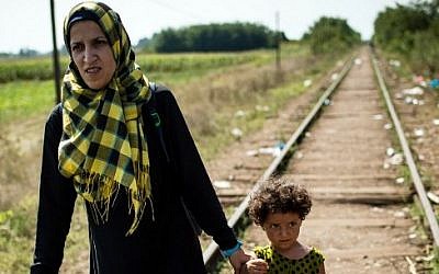 A migrant woman with her daughter walk down a railroad track towards the Hungarian border near the northern Serbian town of Horgos on August 27, 2015. (AFP PHOTO / ANDREJ ISAKOVIC)