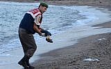 A Turkish police officer carries a migrant child's dead body off the shores in Bodrum, southern Turkey, on September 2, 2015 after a boat carrying refugees sank. (AFP/DOGAN NEWS AGENCY)