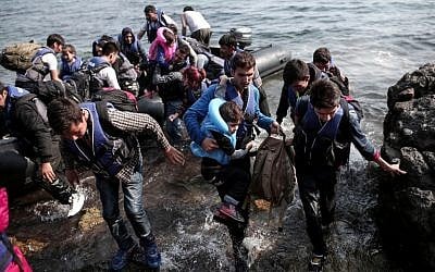 Syrian refugees land on the shores of the Greek island of Lesbos in an inflatable dingy across the Aegean Sea from Turkey, September 3, 2015. (AFP/Angelos Tzortzinis)