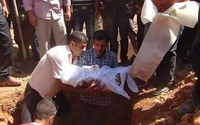 Abdullah Kurdi, center, whose wife and children drowned while trying to reach Kos from Turkey, holds the body of his child during a funeral ceremony in Kobani, on September 4, 2015. (AFP PHOTO / STRINGER)