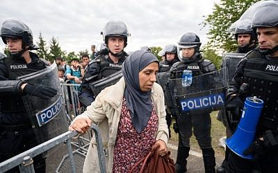 A migrant woman is taken by Slovenian police officers from the Rigonce-Harmica border crossing to the registration center in the nearby Slovenian town of Brezice, on September 19, 2015 in Rigonce. AFP / JURE MAKOVEC)