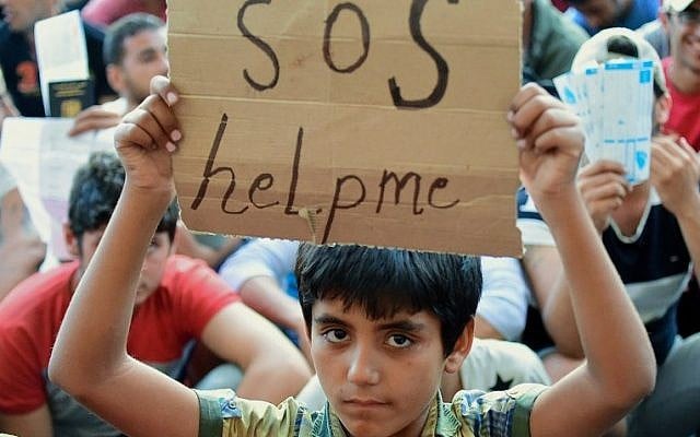 A migrant boy holds a sign reading 'SOS help me' as he sits with other migrants in front of the Keleti (East) railway station in Budapest on September 2, 2015. (AFP PHOTO / ATTILA KISBENEDEK) A migrant boy holds a sign reading 'SOS help me' as he sits with other migrants in front of the Keleti (East) railway station in Budapest on September 2, 2015. (AFP PHOTO / ATTILA KISBENEDEK)
