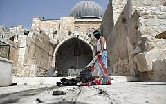 A masked Palestinian wearing a Hamas headband takes a burnt carpet out of Al-Aqsa mosque in Jerusalem's Old City during clashes at the compound on September 13, 2015, just hours before the start of the Jewish new year. (AFP PHOTO/AHMAD GHARABLI)