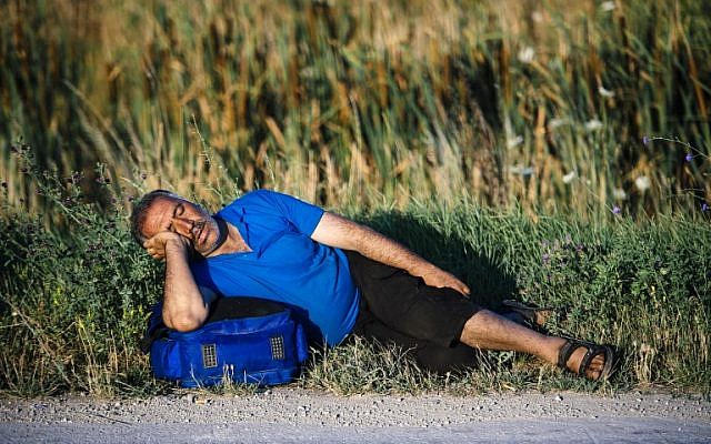A migrant sleeps on a road near the southern Serbian town of Presevo, near the border with Macedonia, on July 15, 2015. (AFP/DIMITAR DILKOFF) A migrant sleeps on a road near the southern Serbian town of Presevo, near the border with Macedonia, on July 15, 2015. (AFP/DIMITAR DILKOFF)