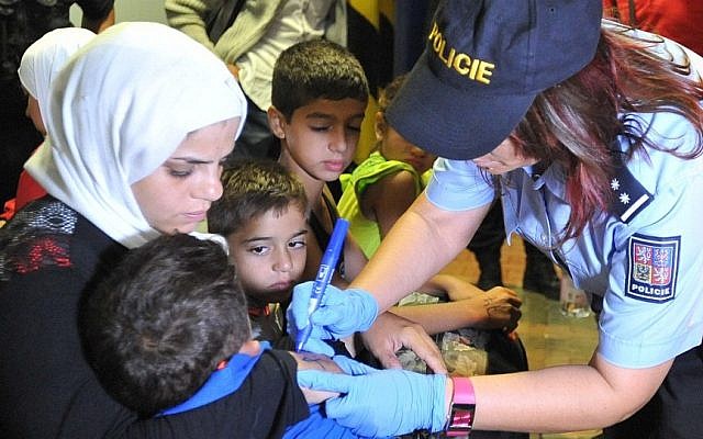 A Czech police officer writes on the hands of migrants at Breclav station on September 1, 2015 (AP)