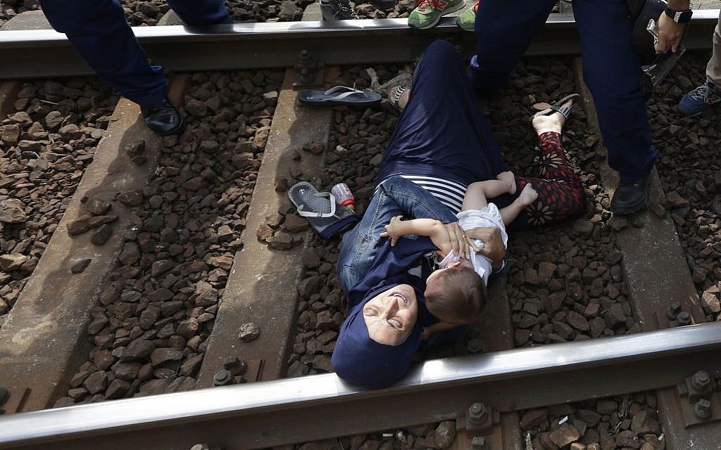 A migrant lies on the track with a baby as she is detained in Bicske, Hungary, Thursday, September 3, 2015. (AP/Petr David Josek)