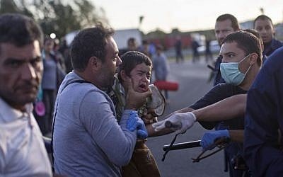 A man holds his child as he tries to talk to Hungarian police officers in Roszke, southern Hungary, Monday, September 7, 2015, inside Hungary, just over the border from Serbia. (Marko Drobnjakovic/AP Photo)