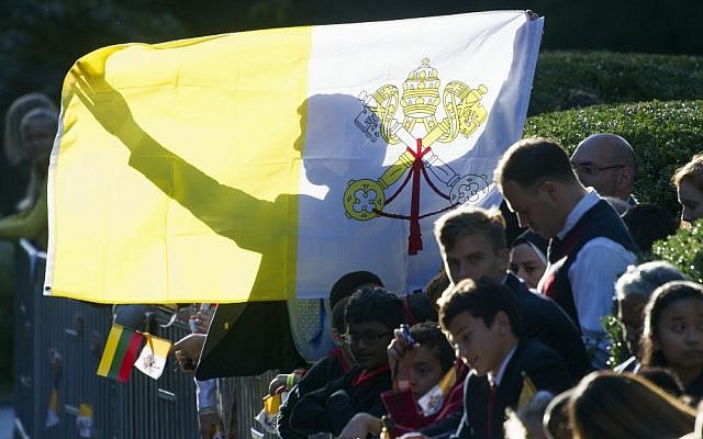 A man holds up a Papal flag as he waits for Pope Francis departure from the Apostolic Nunciature, the Vatican's diplomatic mission in Washington, Sept. 23, 2015. (AP/Cliff Owen) 