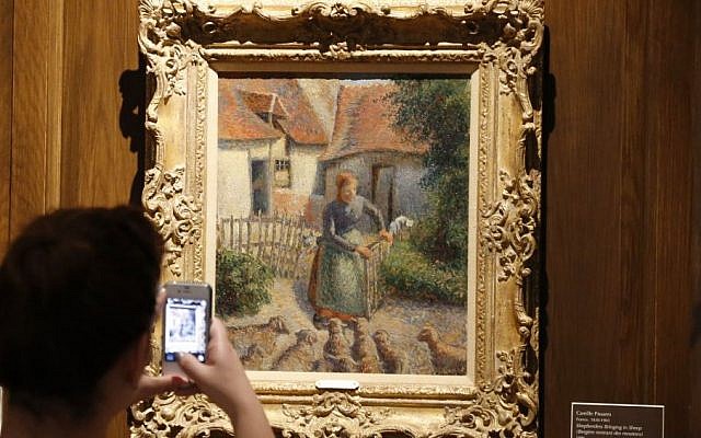 A visitor to the Fred Jones Jr. Museum of Art at the University of Oklahoma takes a photograph of “Shepherdess Bringing in Sheep” by Camille Pissarro on Saturday, February 8, 2014 (Sue Ogrocki/AP, File) A visitor to the Fred Jones Jr. Museum of Art at the University of Oklahoma takes a photograph of “Shepherdess Bringing in Sheep” by Camille Pissarro on Saturday, February 8, 2014 (Sue Ogrocki/AP, File)