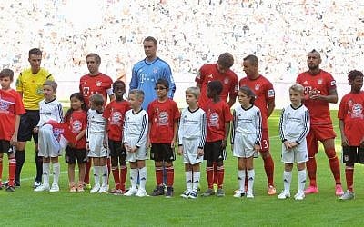 Bayern's players stand with refugee kids on the pitch prior to the German Bundesliga soccer match between FC Bayern Munich and FC Augsburg in the Allianz Arena in Munich, Germany, on Saturday, Sept. 12, 2015 .(Kerstin Joensson/AP) 
