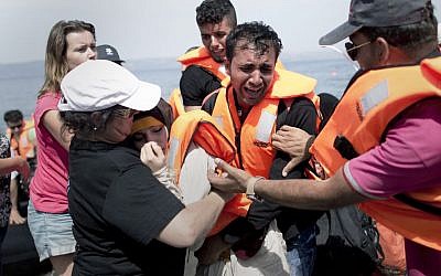 A volunteer helps a Syrian women that collapsed as her husband cries as they arrive aboard a dinghy after crossing from Turkey, on the island of Lesbos, Greece, Monday, September 7, 2015. (Petros Giannakouris/AP)