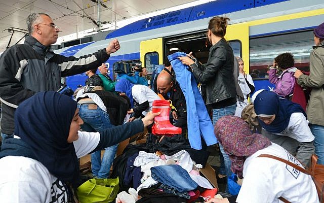 Refugees receive new clothes as they arrive at the Hauptbahnhof station in Salzburg, Austria, Saturday, Sept. 5, 2015 on their way from Hungary via Vienna to Germany. (AP Photo/Kerstin Joensson)