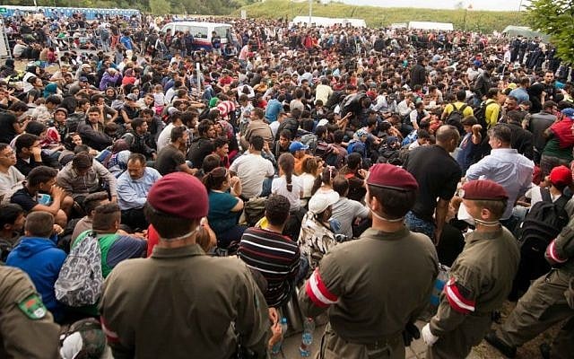 Migrants queue up for buses after they arrived at the border between Austria and Hungary near Heiligenkreuz, about 180 kilometers (110 miles) south of Vienna, Austria, Saturday, Sept. 19, 2015.  (AP/Christian Bruna)