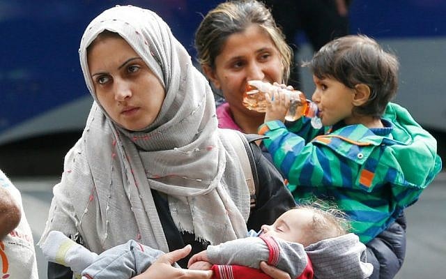 A woman carries her child as they arrive at the main train station in Munich, Germany, Saturday, Sept. 5, 2015. (AP Photo/Michael Probst)