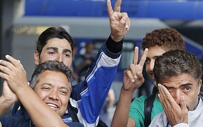 Refugees flash victory signs and wipe away tears as they arrive at the main train station in Munich, Germany, Saturday, Sept. 5, 2015. Hundreds of refugees arrived in various trains to get first registration as asylum seekers in Germany. (AP/Michael Probst)