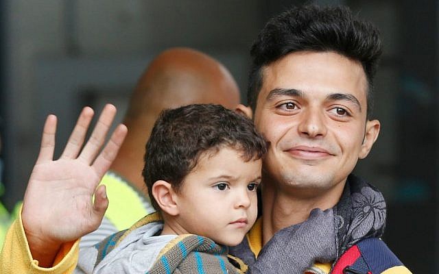 A father carries his child as they arrive at the main train station in Munich, Germany, Saturday, Sept. 5, 2015. (AP Photo/Michael Probst)